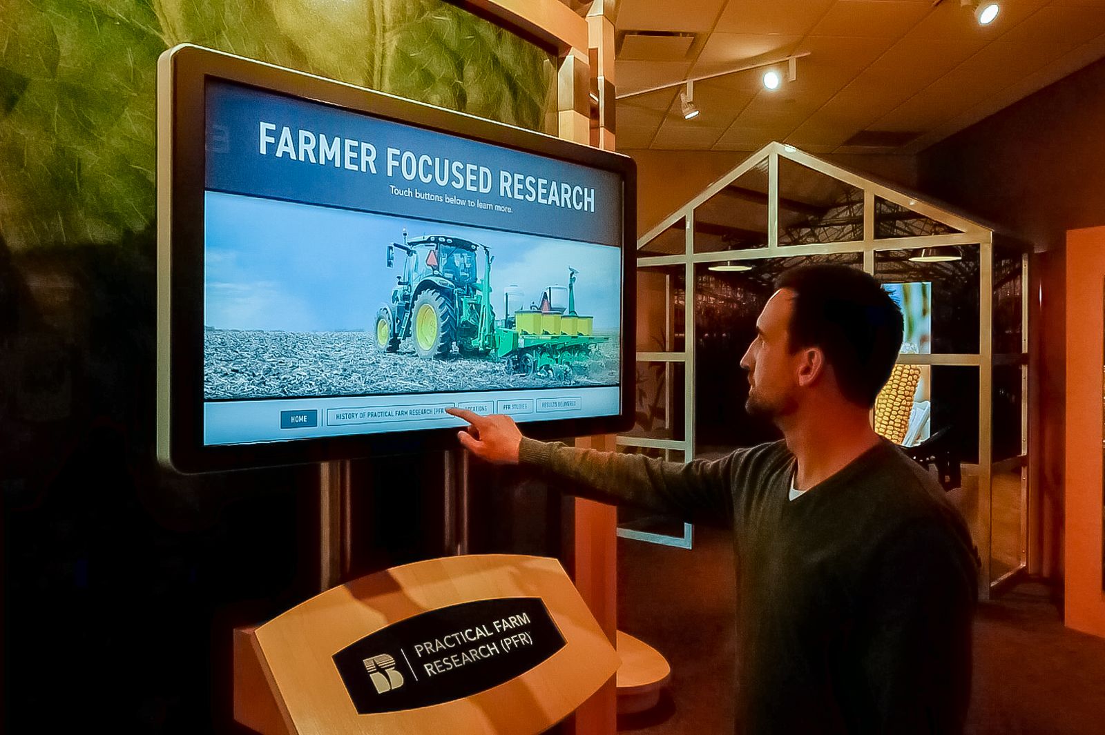 Visitor using a touchscreen 'Farmer Focused Research' interactive display